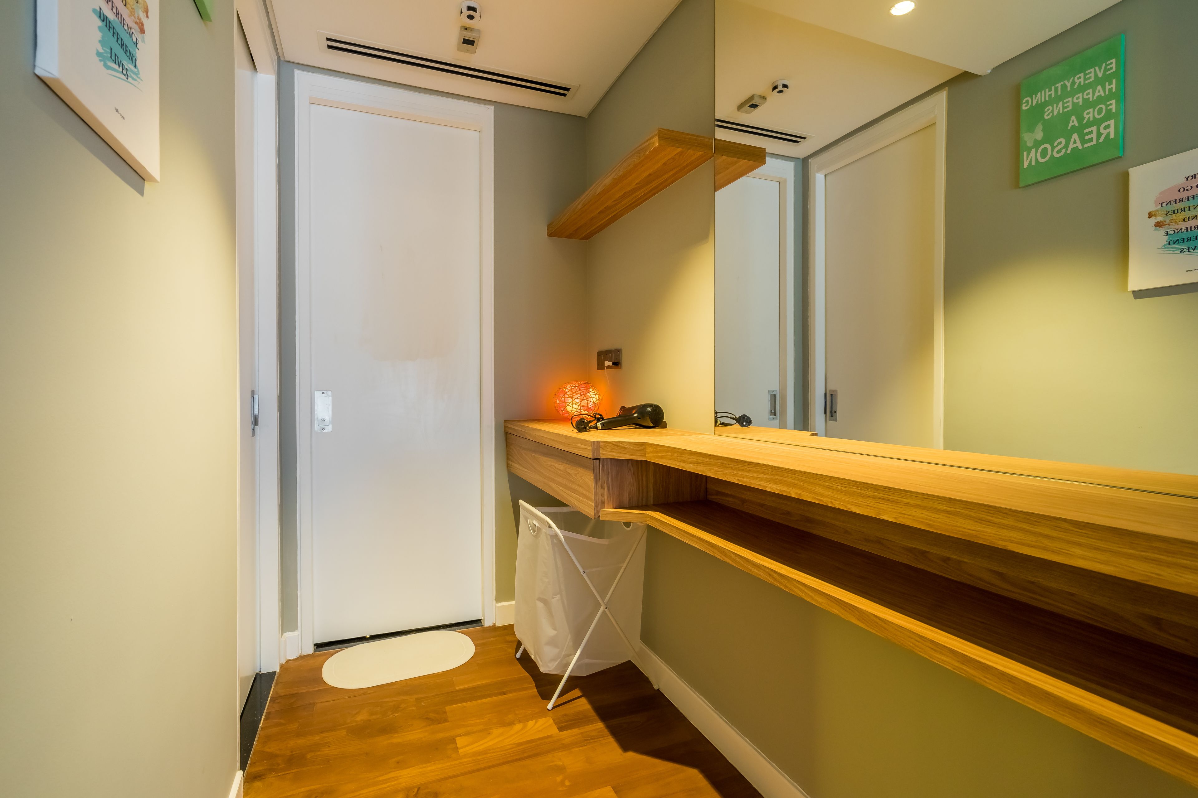 Un couloir avec un banc en bois, une porte blanche et une petite poubelle.