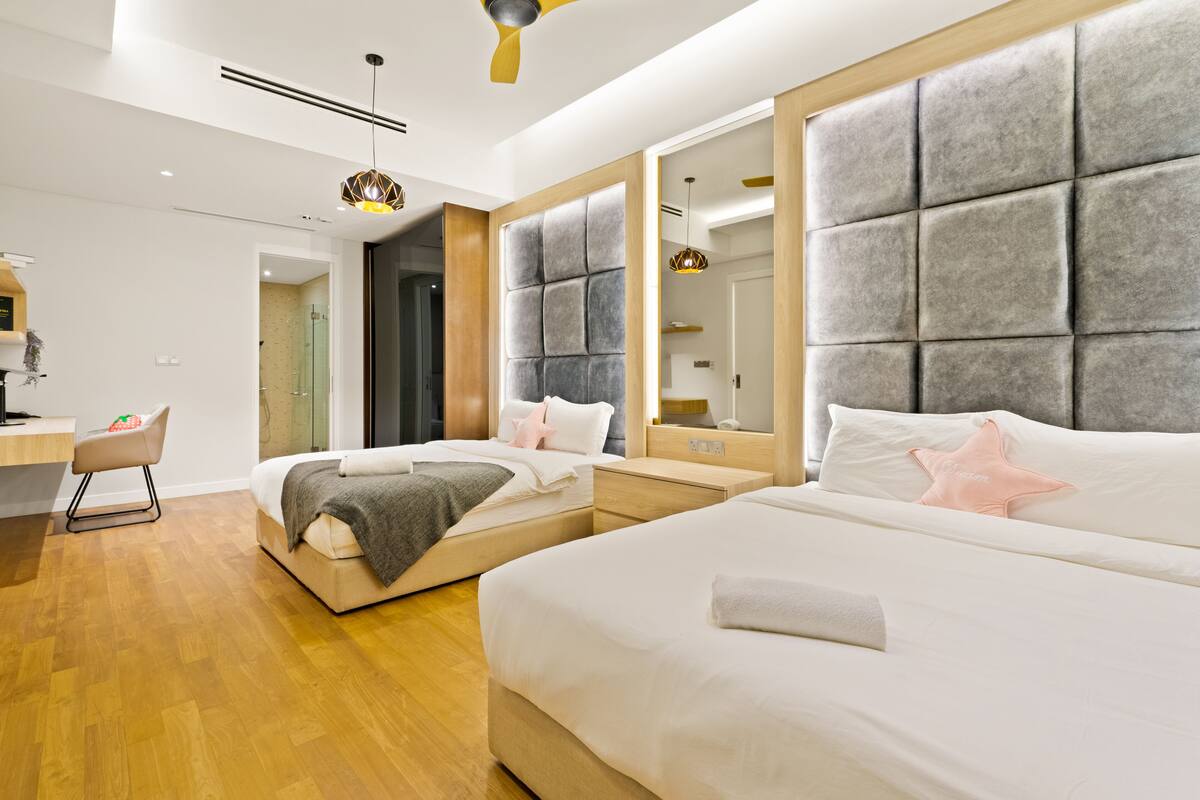 Une chambre d’hôtel moderne avec deux lits, un bureau et un grand miroir.
