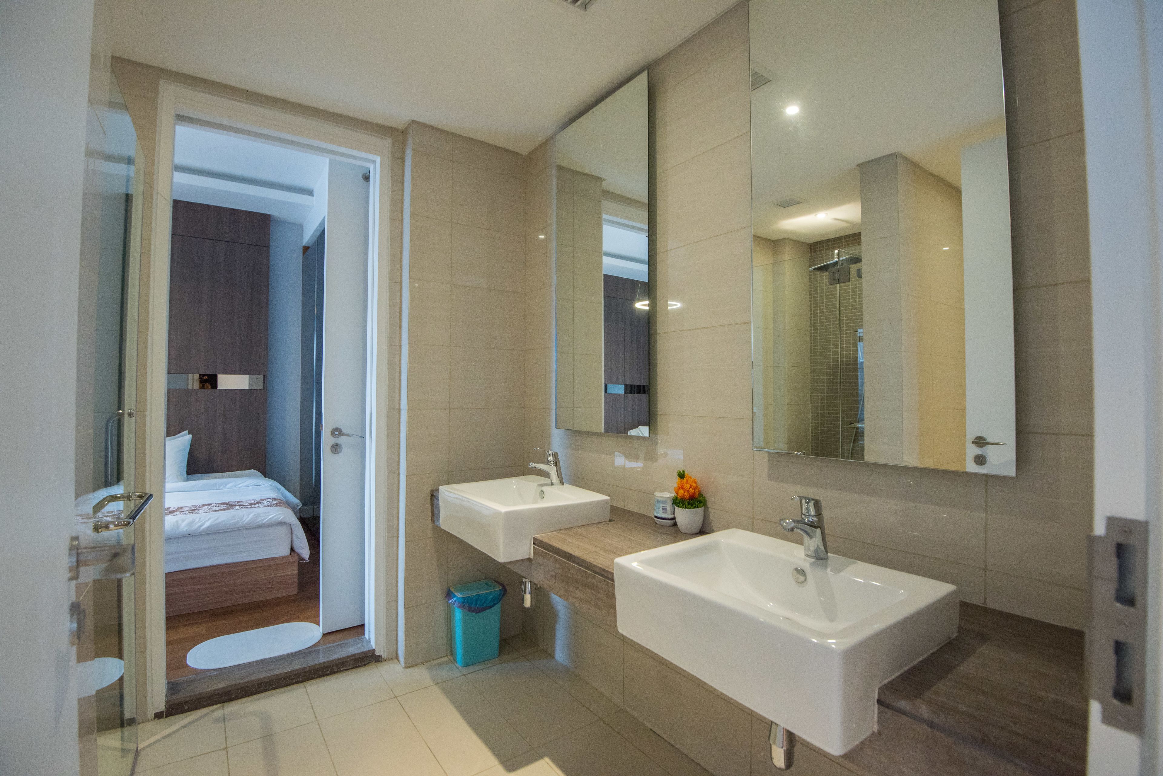 A modern bathroom with two sinks, a large mirror, and a visible shower area.
