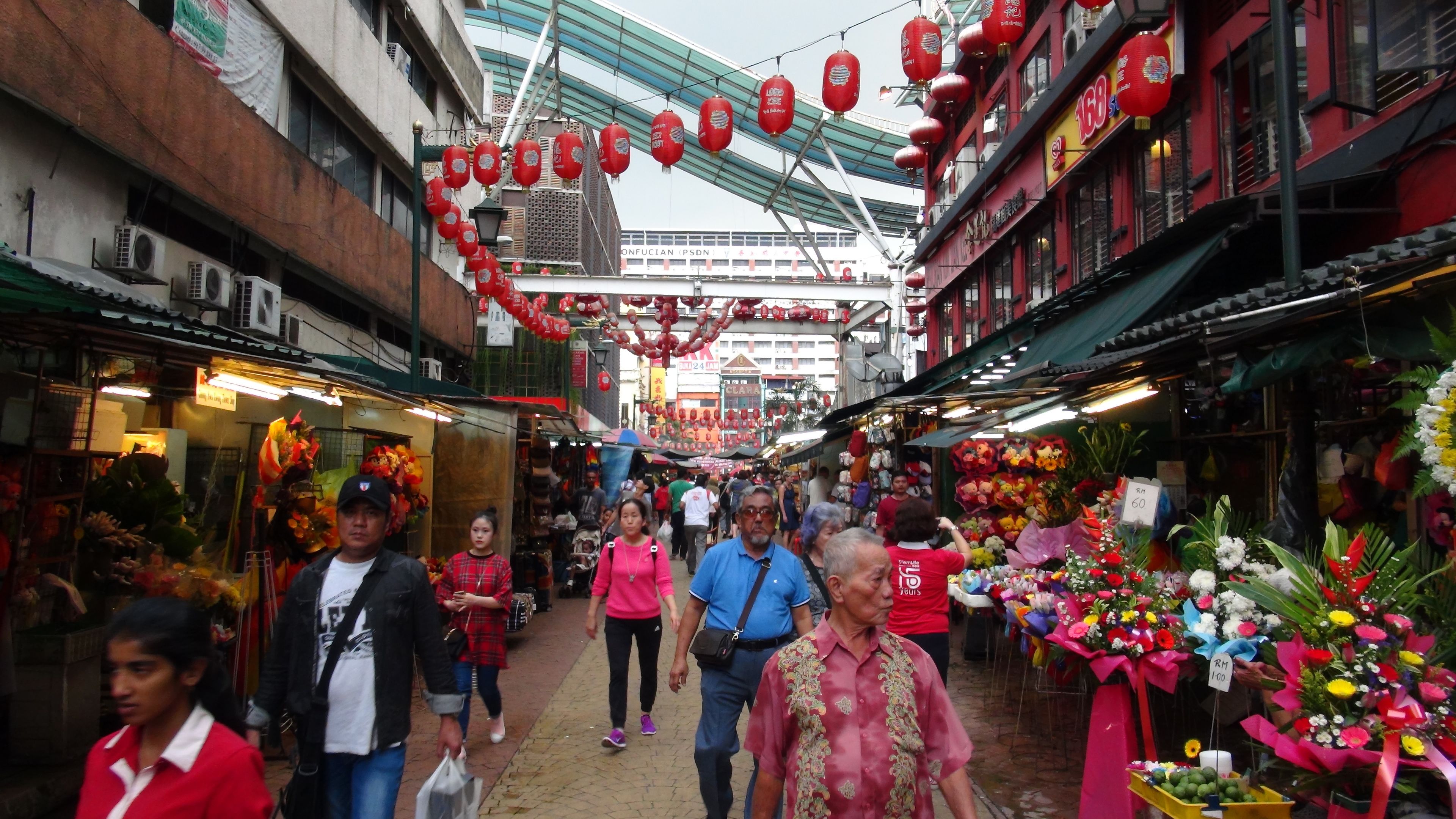 A bustling market street with vendors and shoppers.