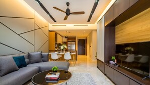 A modern living room with a grey sofa, a coffee table, and a TV on a wooden cabinet. - Anggun Residences Serviced Suites (Kuala Lumpur)