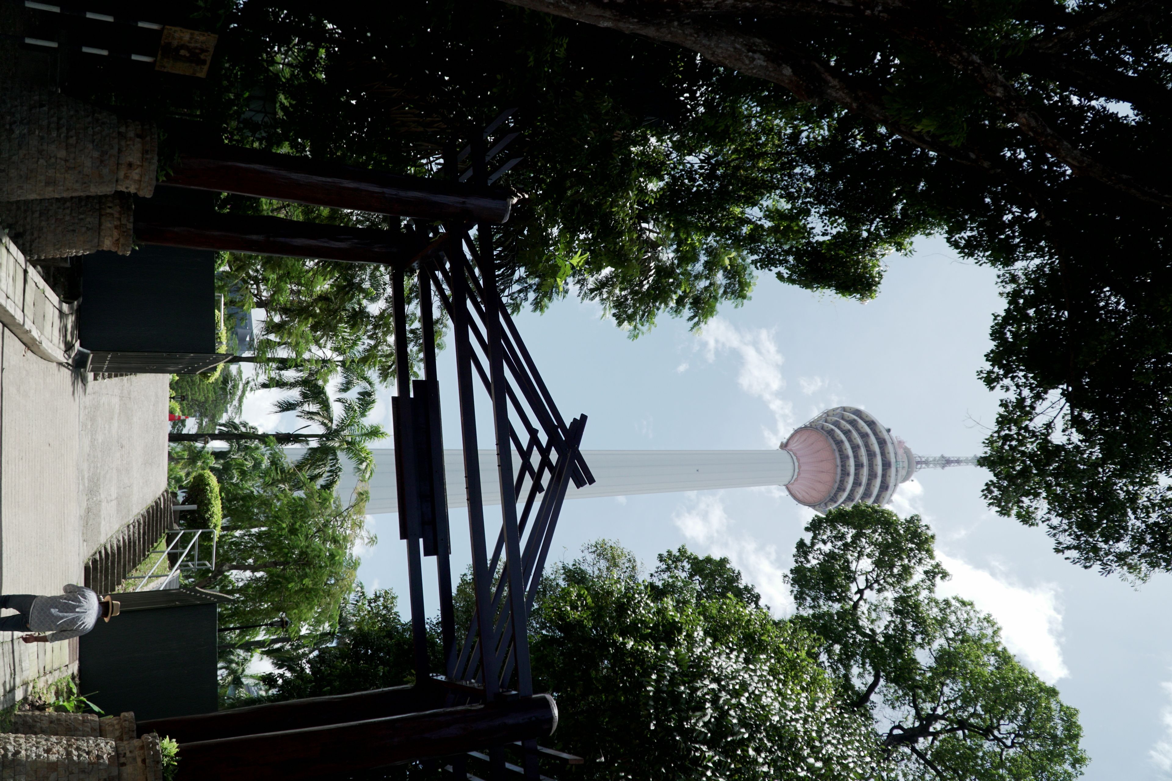 A tower with a spiral design, surrounded by trees and a metal structure.