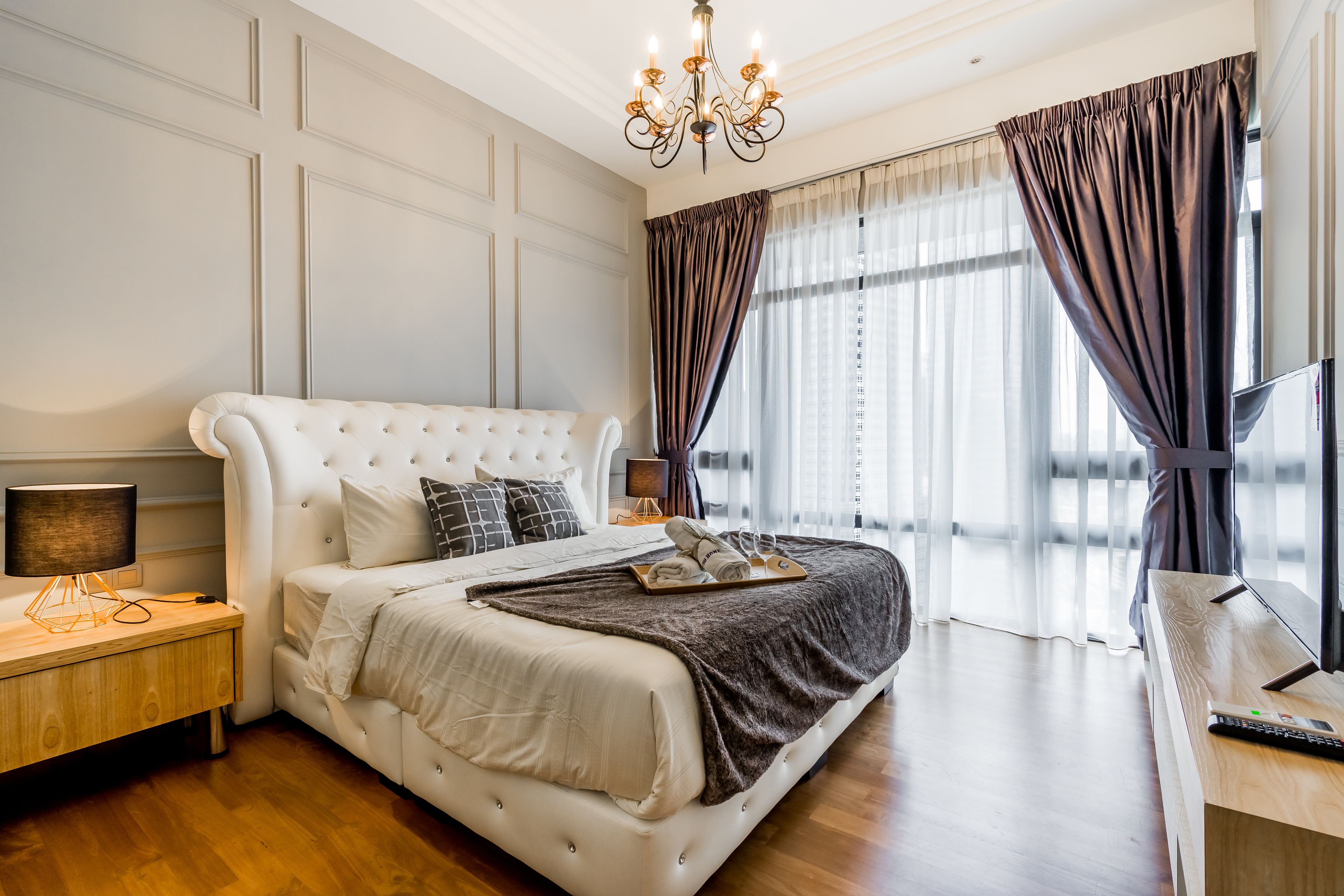 A bedroom with a large bed, a nightstand, a desk, and a TV.