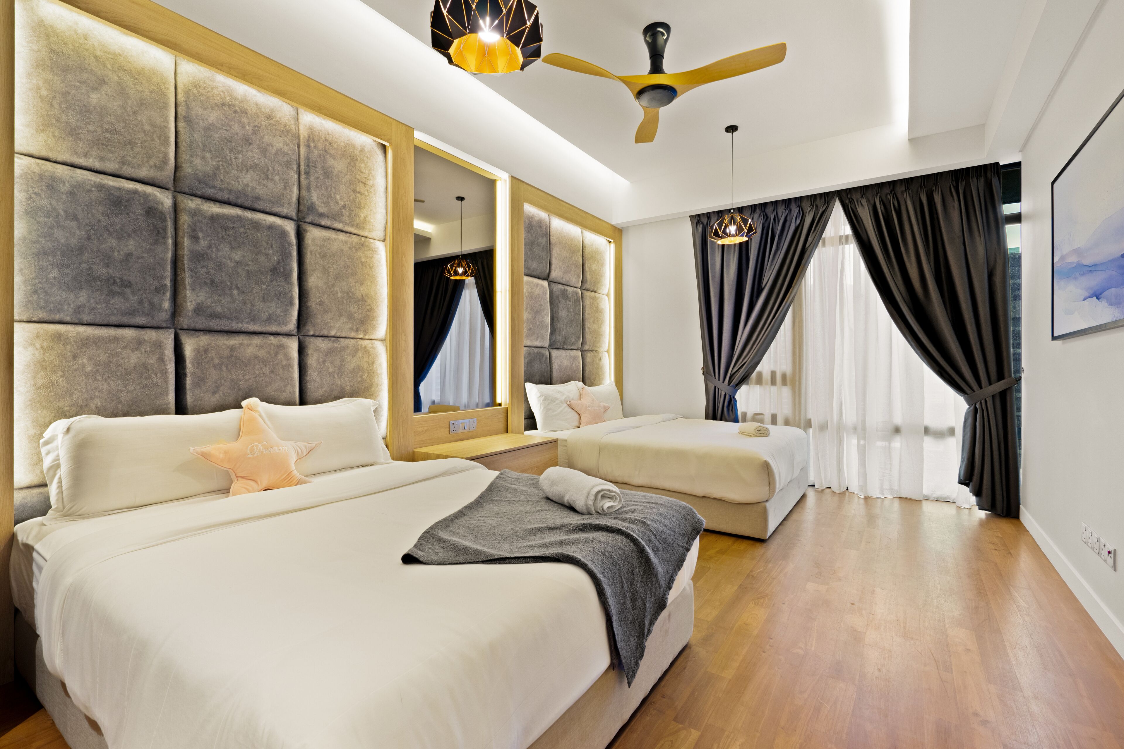 Una habitación de hotel moderna con dos camas, un ventilador de techo y ventanas grandes con cortinas.