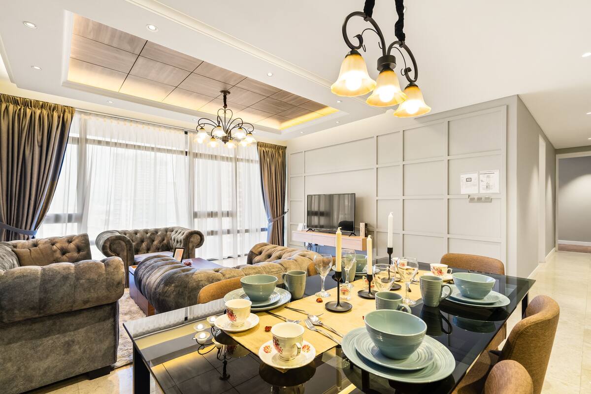 Un salon moderne comprenant un ensemble de canapés, une table à manger pour six personnes et un téléviseur fixé au mur.