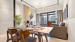 A modern dining area with a wooden table, chairs, and a sofa. - Anggun Residences Serviced Suites (Kuala Lumpur)