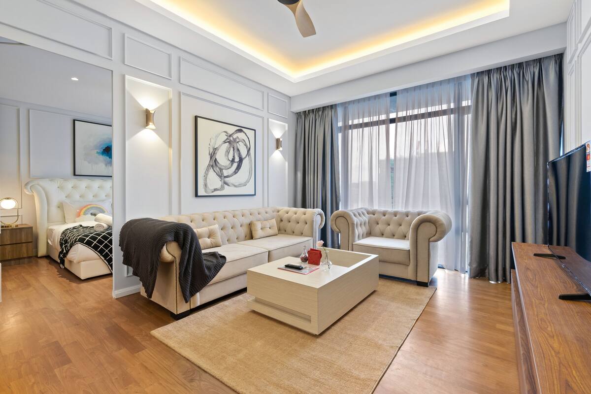 Un salon moderne avec un canapé beige, une table basse blanche et un téléviseur posé sur un meuble en bois.