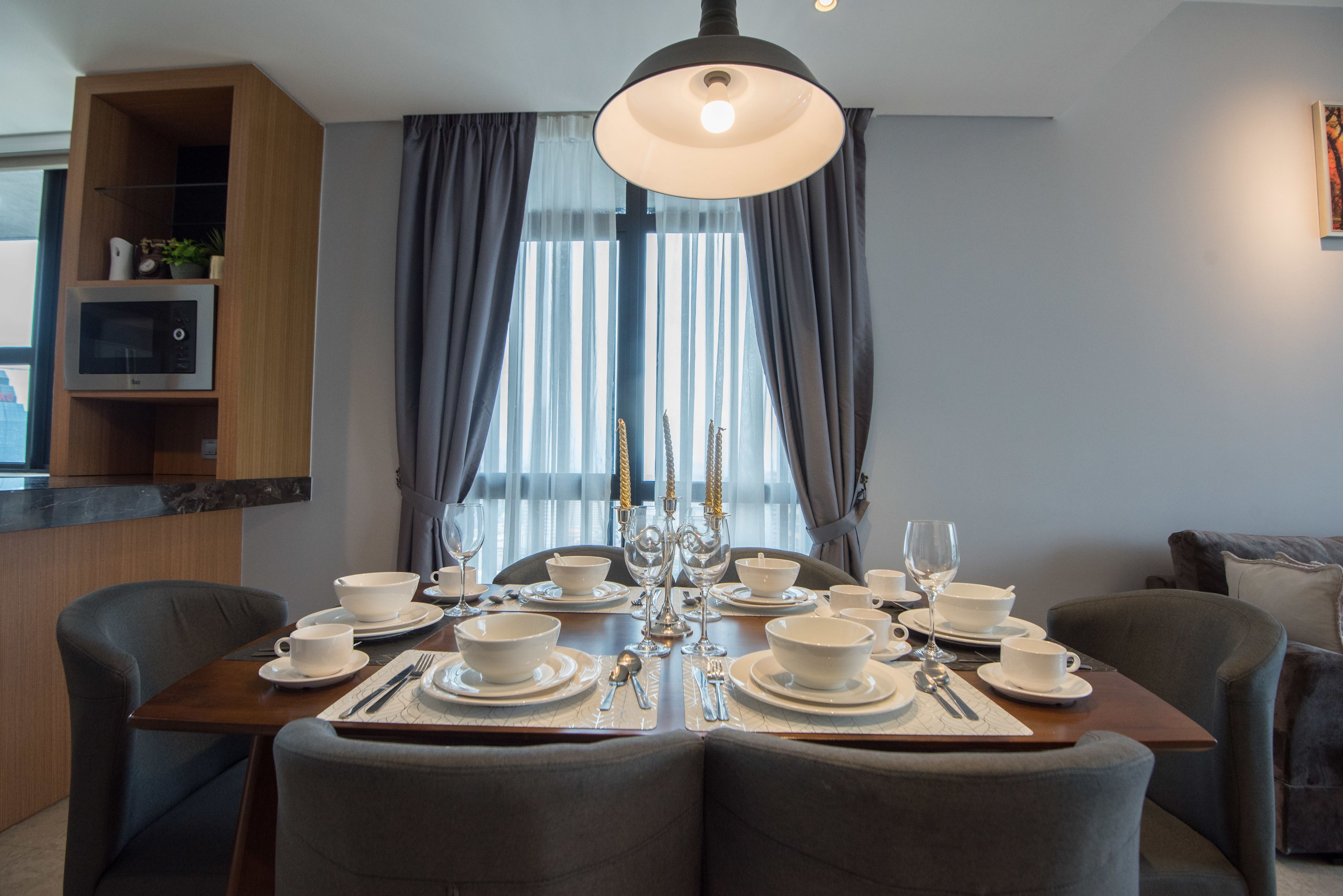 A dining area with a wooden table set for four, equipped with white bowls, plates, and cutlery.