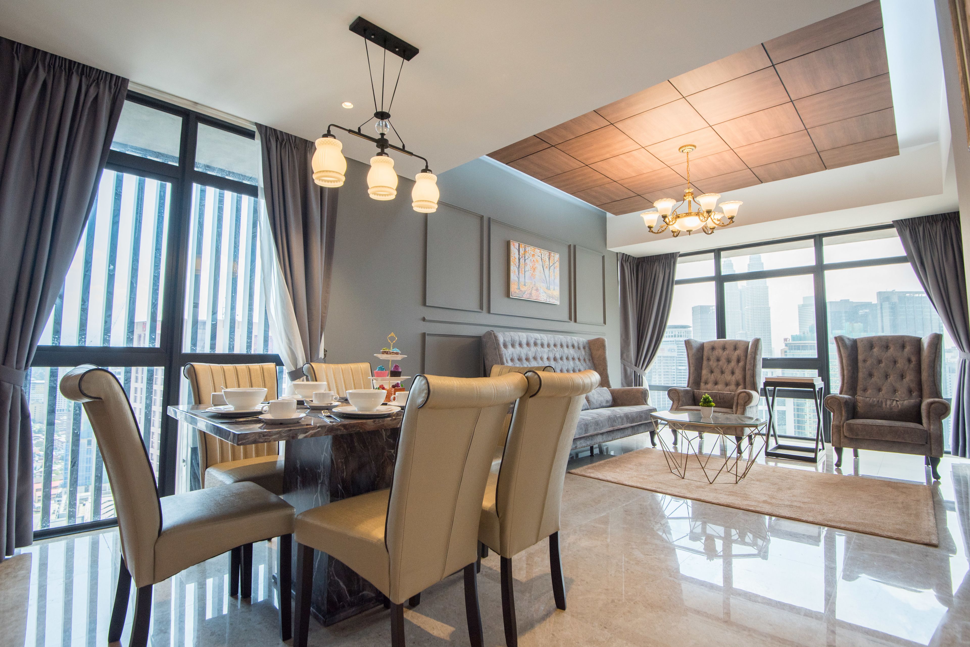 A modern hotel room with a dining area, two seating arrangements, and large windows offering city views.