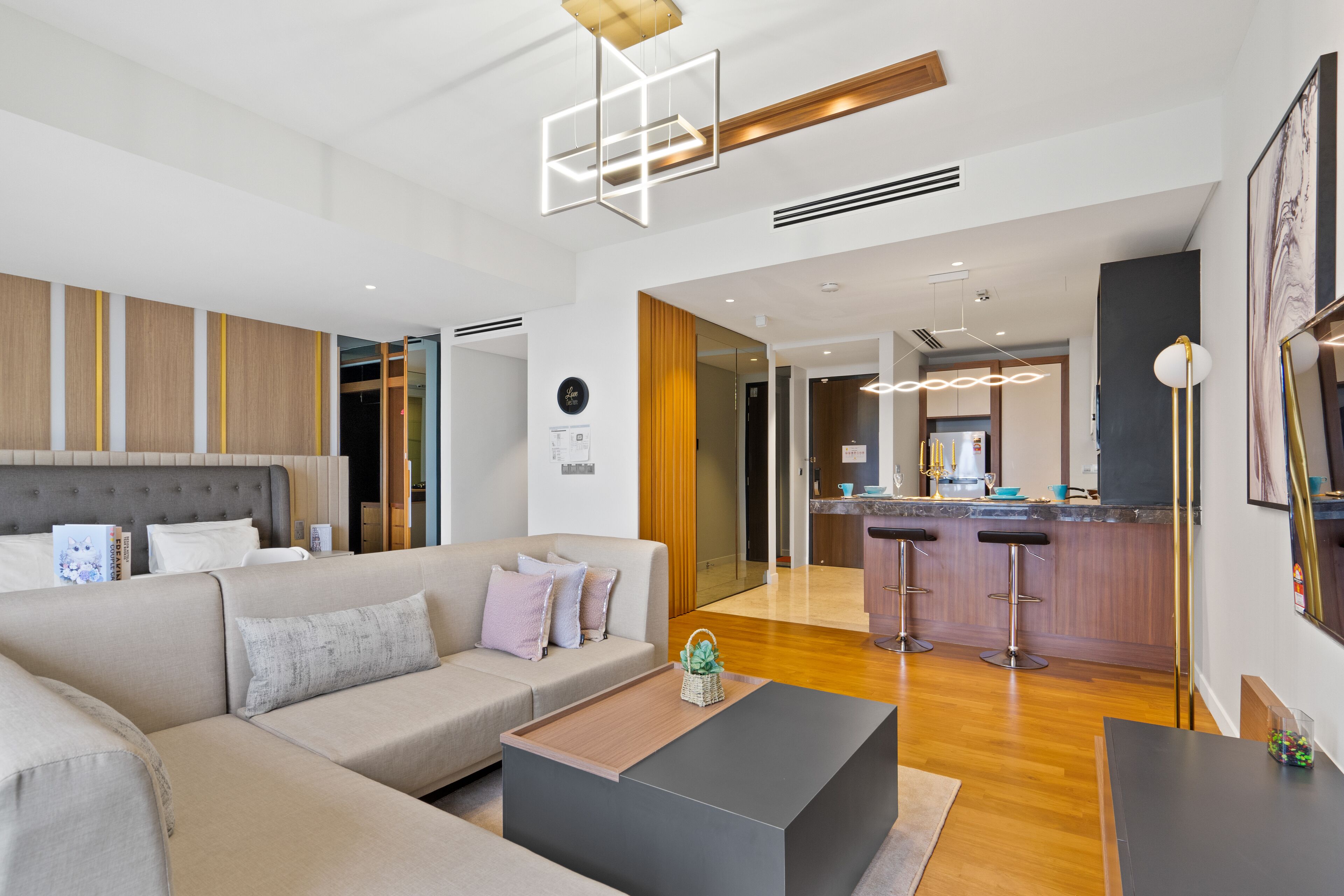 A modern living room with a sofa, coffee table, and a kitchen area in the background.