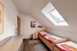 A bedroom with a skylight, a bed with floral bedding, a desk, and a chair. - NATURE and PEACE 🍀 Cozy, quiet 2-room vacation apartment in Münster (Münster)