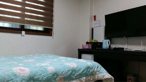 A bedroom with a bed, a desk, a television, and a window with blinds. - Booyoung Motel (Geoje)