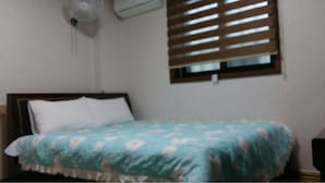A bedroom with a bed, a window with blinds, and an air conditioning unit on the wall. - Booyoung Motel (Geoje)