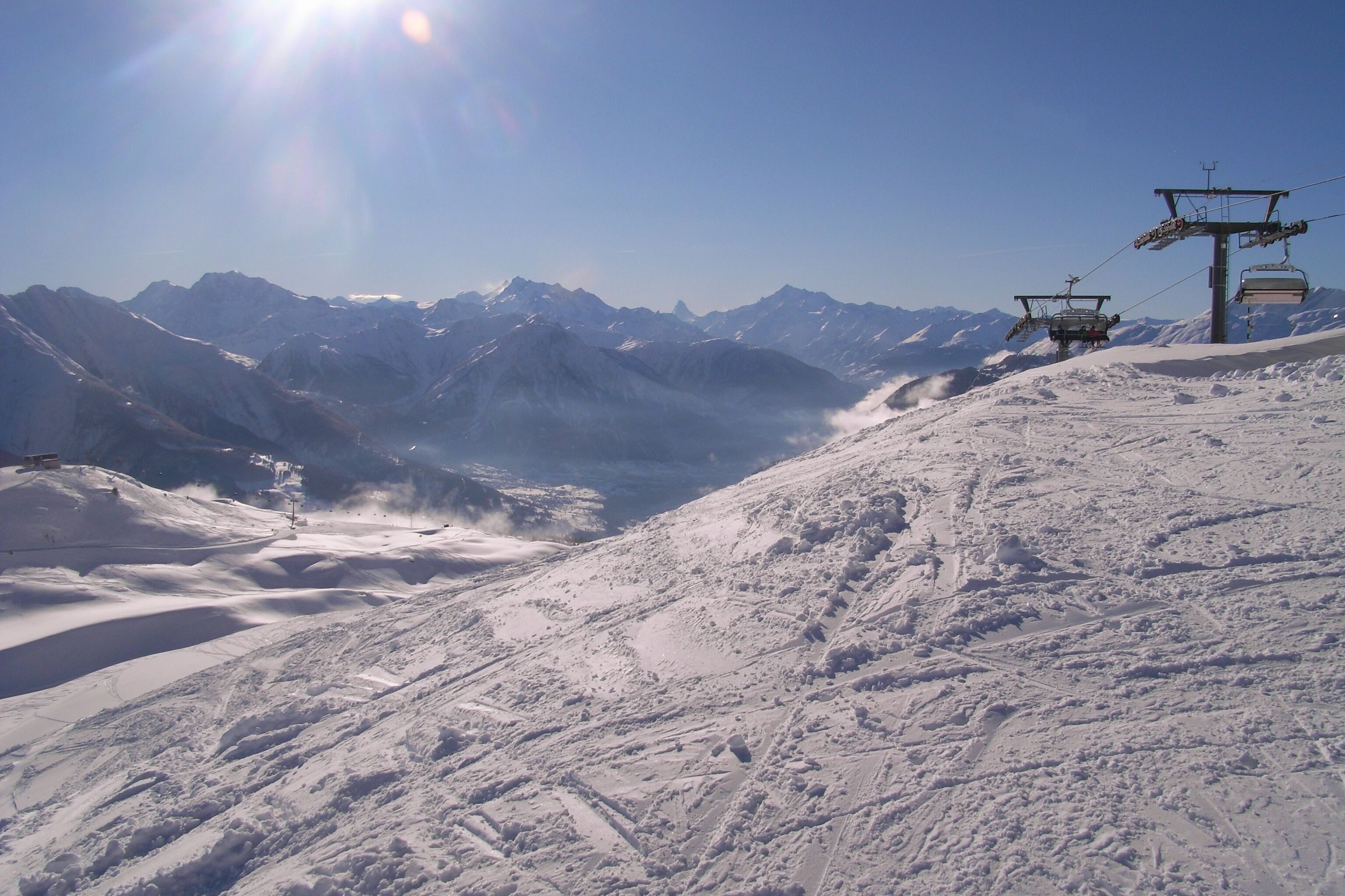 A snowy mountain landscape with ski lifts and a clear sky.
