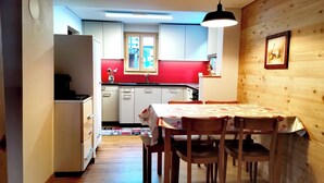 Une cuisine compacte avec des meubles blancs, un pare-feu rouge et un coin repas comprenant une table et des chaises.
