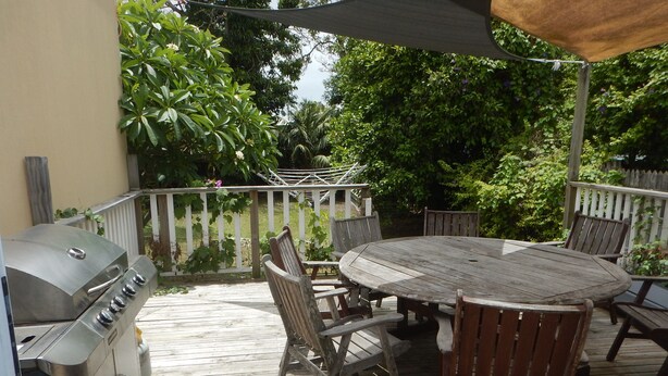 En træterrasse med grill, et rundt bord og stole.