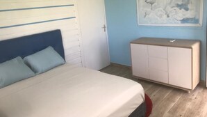 A bedroom with a bed, a white wardrobe, and a painting of clouds on the wall.