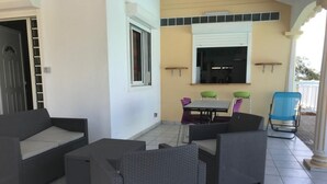 A patio area with wicker furniture, a table, and chairs.