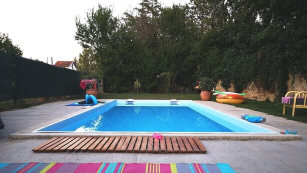 Una piscina con cubierta de madera y colchonetas de colores.