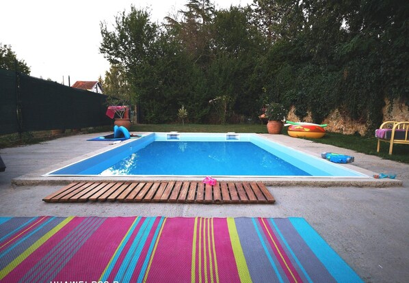 Une piscine dotée d’une terrasse en bois et de tapis colorés.