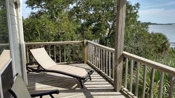 Terraza de madera con dos sillones de descanso y baranda con vista al agua.