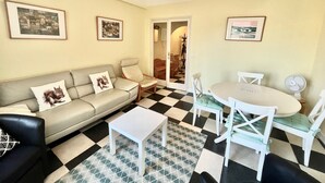A living room with a sofa, a small table, a dining table with chairs, and a patterned rug. - 45 clemenceau (Cannes)