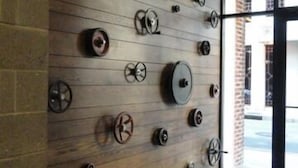 A wall with multiple wheels and a large pot, a wooden floor, and a glass door leading outside. - Luxury Loft in Downtown Asheville: chic, central, in the middle of all the fun! (Asheville)