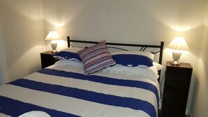 A bed with striped bedding and two bedside lamps. - Sailor's Rest Holiday House (Lota)