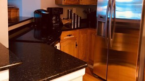 Une cuisine moderne avec des meubles en bois, un réfrigérateur en acier inoxydable et une machine à café.
