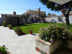 A courtyard with a tiled patio, potted plants, and a grassy lawn. - Your holiday in Mi Naranjo Mediterranean villa (Orihuela)