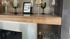 A wooden shelf with various wine glasses and a framed sign that reads "Wine a little, laugh a lot." - Breezy Studio, footsteps from the beach.  (Negril)