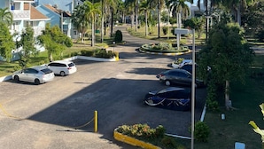 A parking lot with several cars, surrounded by palm trees and greenery. - Breezy Studio, footsteps from the beach.  (Negril)