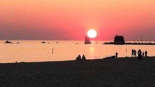 A sunset over a beach with boats and a few people on the shore. - Charming House Located In Downtown Grand Haven (Grand Haven)