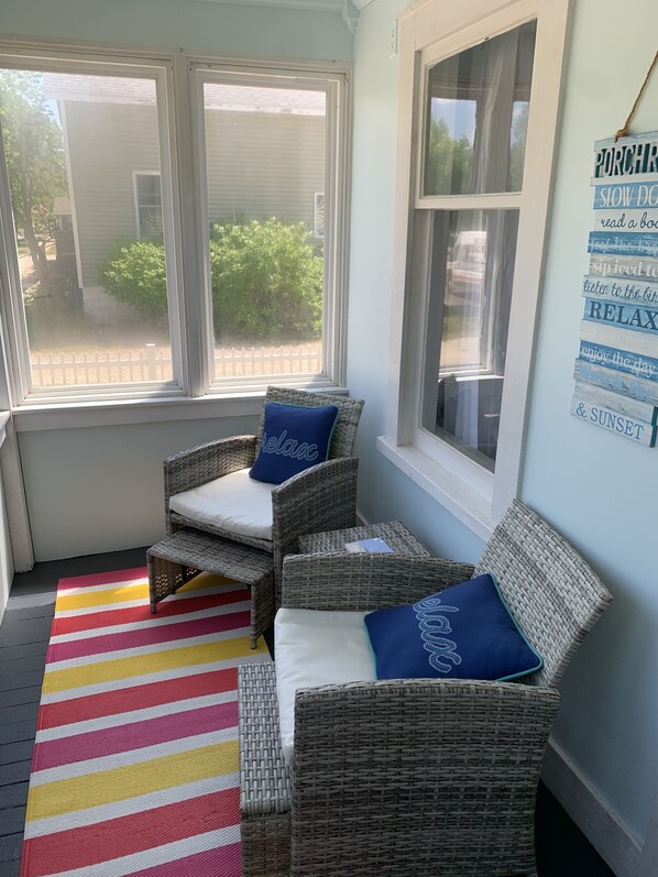 A cozy seating area with wicker chairs and a colorful striped rug.