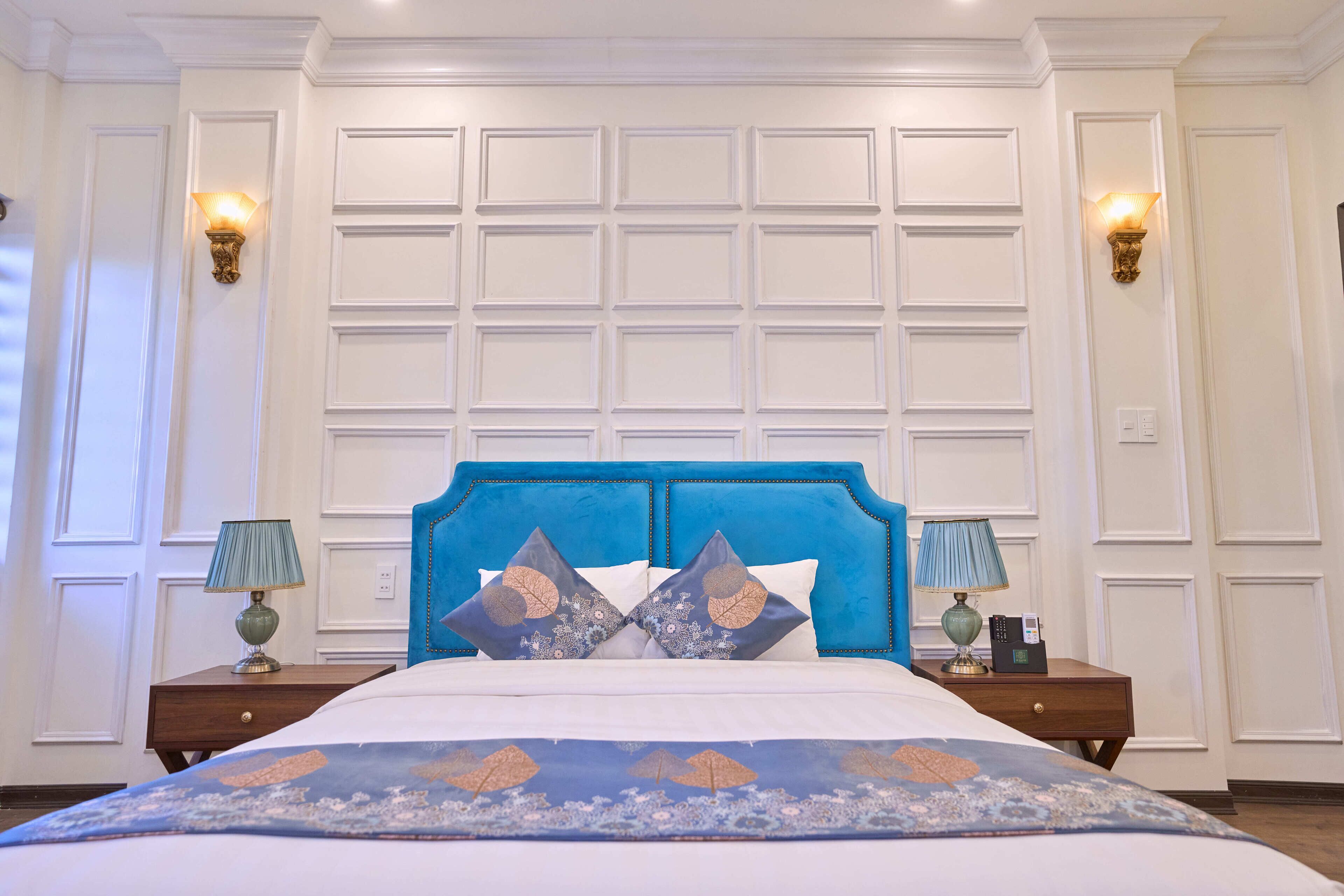 Une chambre à coucher avec une tête de lit bleue, des murs blancs et une couvre-lit à motifs.