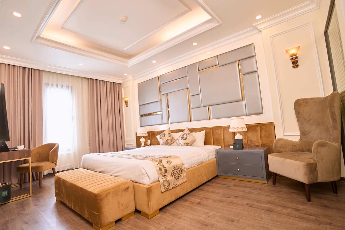 Een hotelkamer met een groot bed, een bureau, een stoel, een nachtkastje en een televisie.