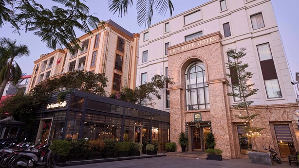 A hotel with a modern facade, a cafe, and a well-maintained outdoor area with plants. -  Le Haute Hotel Hai Phong (Hai Phong)