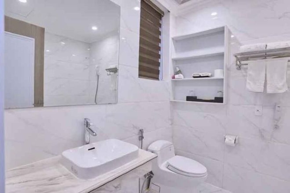 Une salle de bain moderne avec un lavabo, des toilettes et une douche, le tout de couleur blanche.