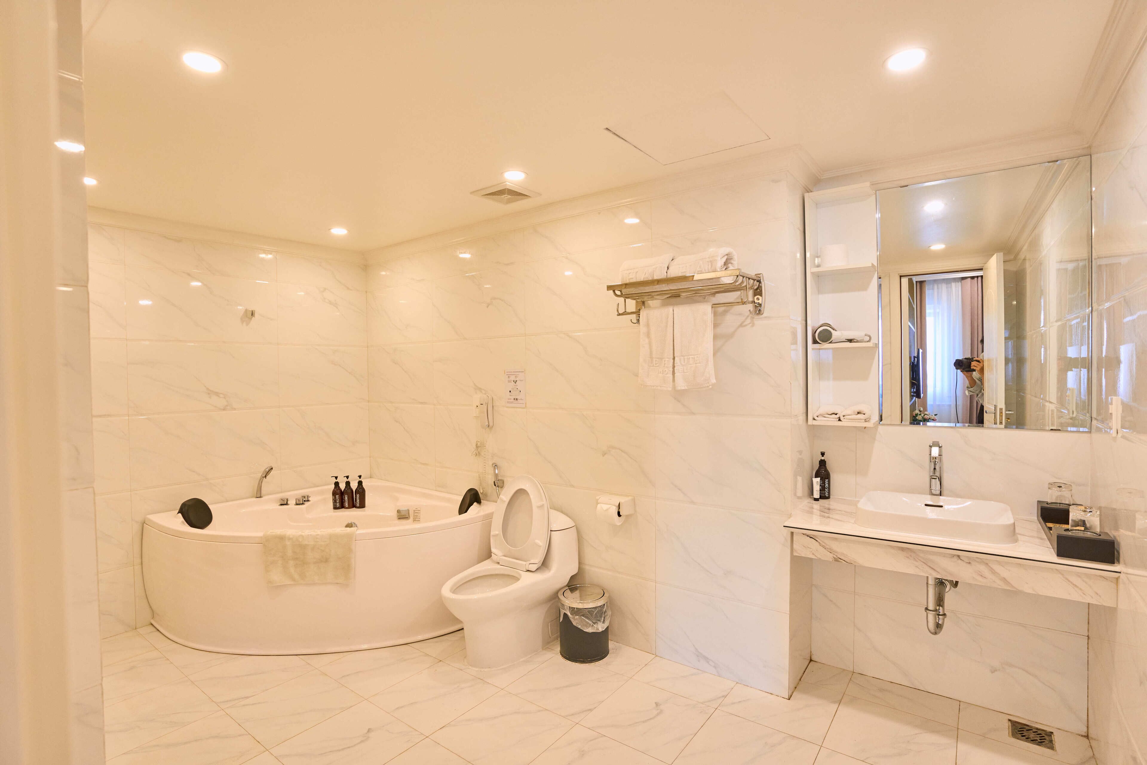 A modern bathroom with a freestanding bathtub, a toilet, a sink, and a large mirror.