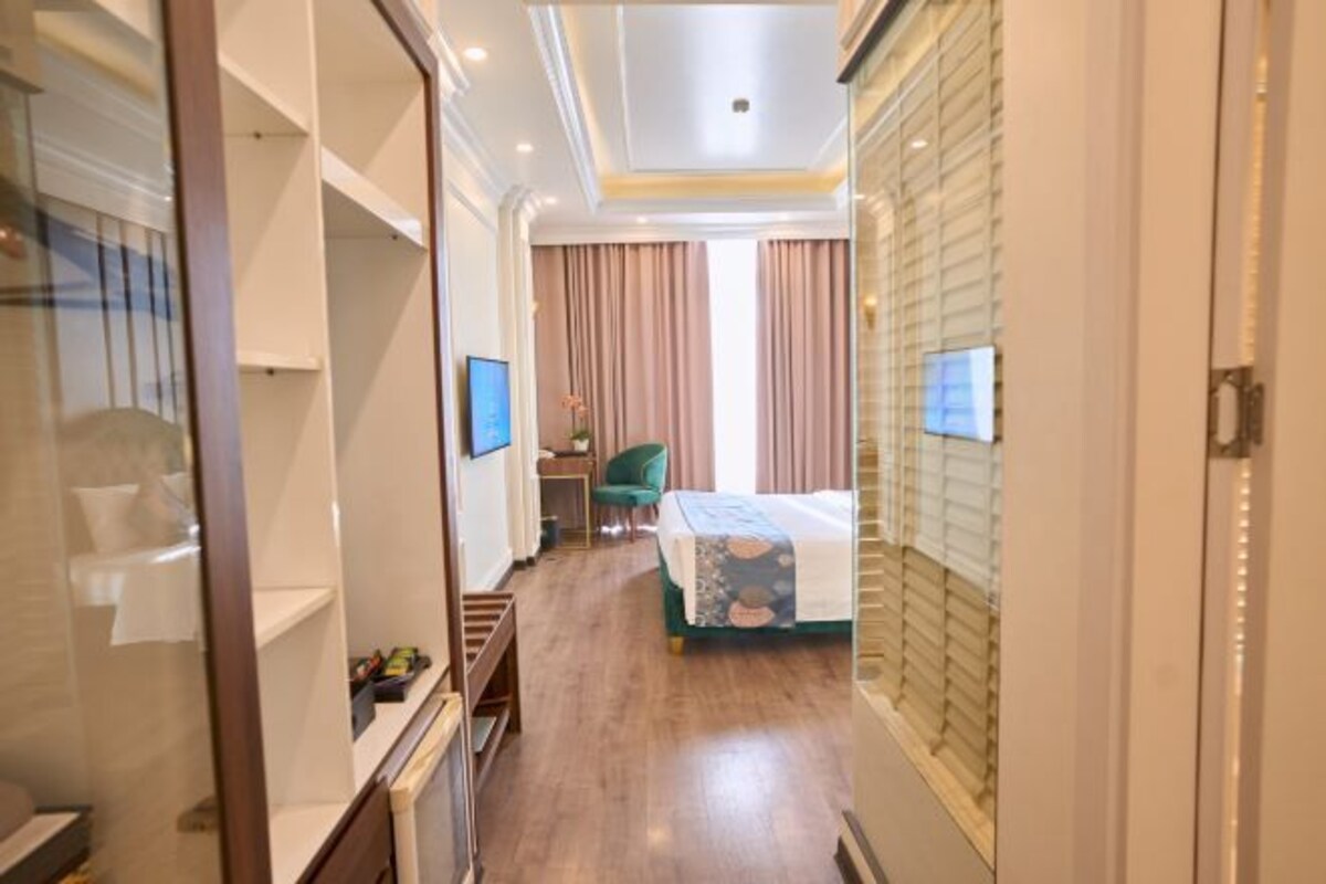 Une chambre d’hôtel avec un lit, un bureau, une chaise et un téléviseur.