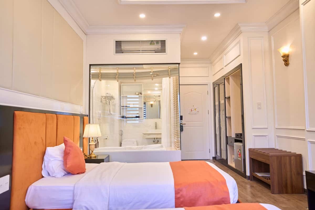Een hotelkamer met twee bedden, een badkamer en een kledingkast.