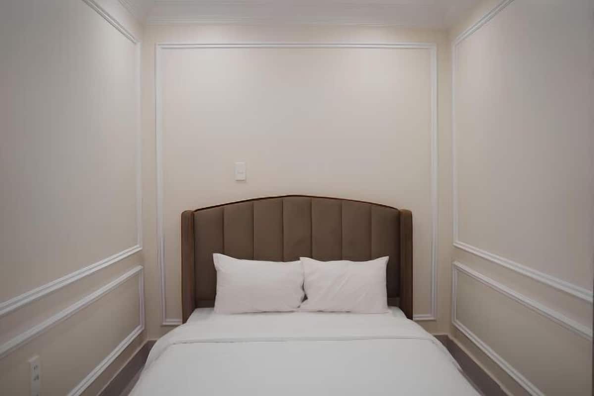 Een hotelkamer met een groot bed, een houten hoofdeinde en witte beddengoed.