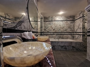 A modern bathroom with marble walls, a large bathtub, and two large bowls as sinks. - Chanthapanya Hotel (Vientiane)