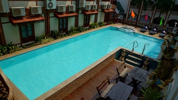 Una piscina al aire libre, sillones reclinables de piscina