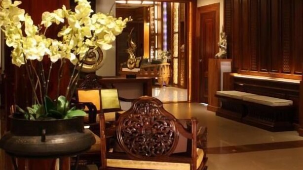 A traditional interior with a wooden dining table, ornate chairs, and a potted orchid. - Chanthapanya Hotel (Vientiane)