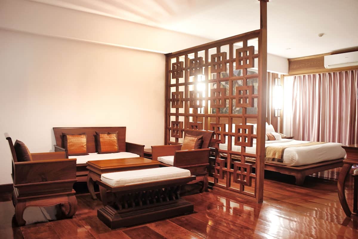 A traditional room with a wooden bed, a wooden desk, a wooden chair, and a wooden sofa.