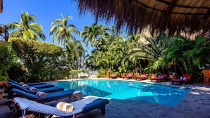 Un área de piscina con sillas de descanso y palmeras.