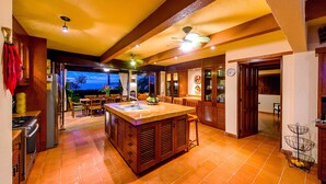 Una cocina con una isla central, armarios de madera y un comedor con vistas.