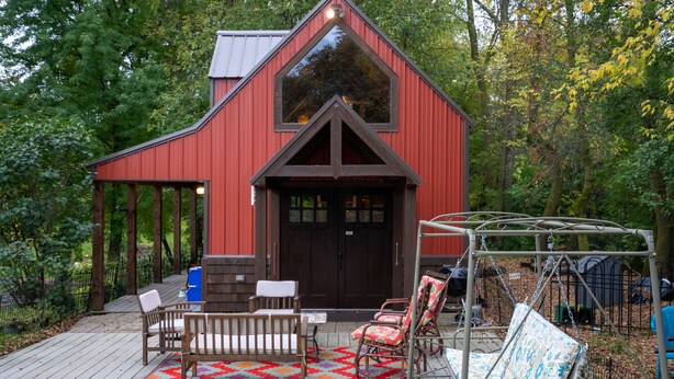 A red barn with a large window and a door, a wooden deck with a bench and chairs, and a swing set. - Wizard's LOTR Cabin: New Treehouse Addition! Pet-friendly.  (Holdingford)