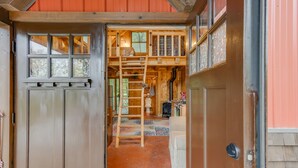 A wooden interior with a ladder leading to a loft area, a fireplace, and a cozy seating area. - Wizard's LOTR Cabin: New Treehouse Addition! Pet-friendly.  (Holdingford)